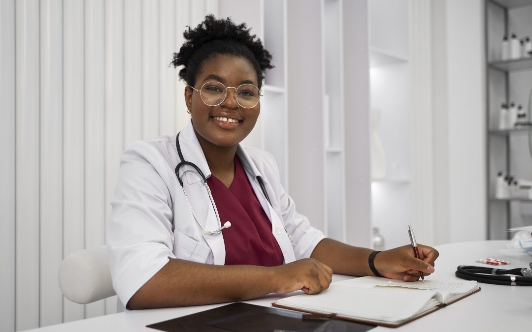 a female doctor sits at a desk writing in a notebook