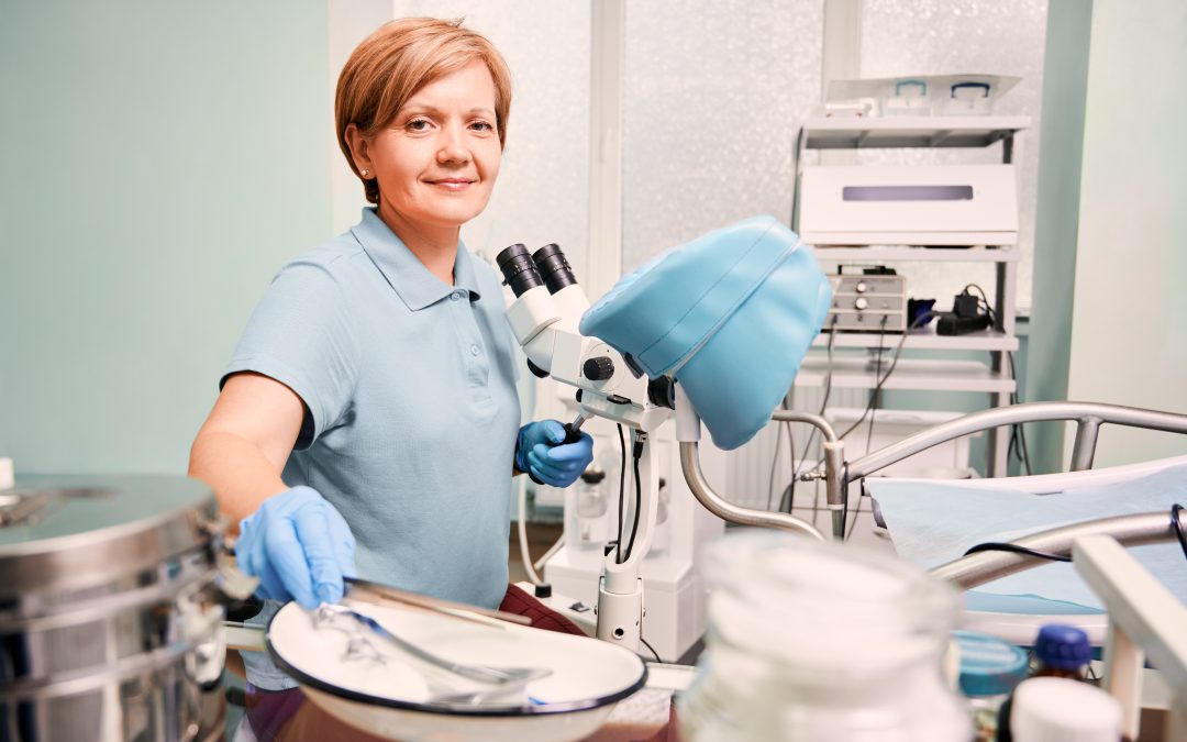 Doctor in sterile gloves working in gynecological cabinet. Woman doctor using colposcope and grabbing pincers while sitting in front of chair. Concept if gynecology, obstetrics and medical workers.